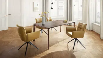 Helles Esszimmer in einer Altbauwohnung mit einem modernen Holzesstisch und Designer Armlehnstühlen mit senfgelben Lederbezügen und schwarzem Fußgestell.