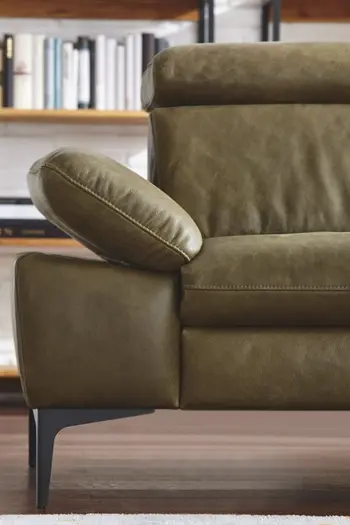 Linke Hälfte eines grünen Ledersofas mit aufgestellter Armlehne und klappbarer Kopflehne.