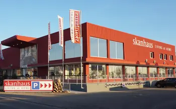 Hausfassade von Möbel Skanhaus mit Flaggenmasten und Firmenschild.