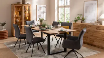 Gemütliches Esszimmer mit Massivholz Esstisch, um den graue Stühle mit und ohne Armlehne stehen.