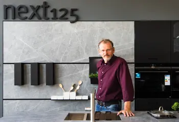 Mitarbeiter präsentiert sich stolz vor einer Next125 Küche