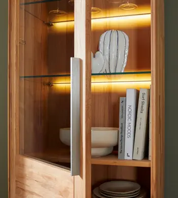 Geöffnete helle Vitrine aus Kernbuche mit Glas Regalböden und Beleuchtung.