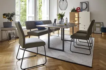 Moderne grüne Sitzbank mit Lederbezug und schwarzem Fußgestell an einem schwarzen Esstisch, an dem noch drei dazu passende grüne Lederstühle mit schwarzem Fußgestell stehen.