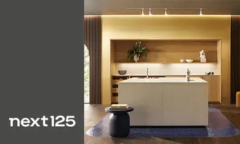 Minimalistische weiße Küche mit Insel und Einbauschrank von next125. Im Bild das Logo von next125 auf grauem Hintergrund.&nbsp;&nbsp;