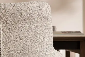 Nahansicht des oberen Teils der Rückenlehne eines grauen Armlehnstuhls.