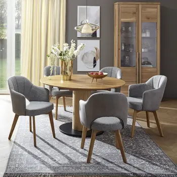 Ovaler Massivholz Esstisch, um den graue Armlehnstühle stehen.