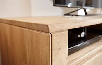 Nahaufnahme eines modernen TV-Lowboards aus massivem Holz – exakte Kantenverarbeitung und natürliche Holzmaserung für stilvolle Wohnzimmermöbel mit langlebiger Qualität und elegantem Design.