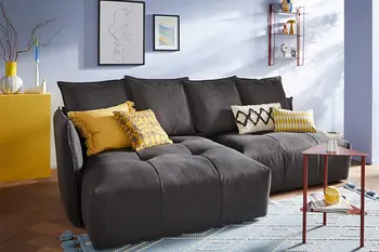 Dunkelgraues Sofa mit vielen Kissen am Rücken und gelben Dekokissen.