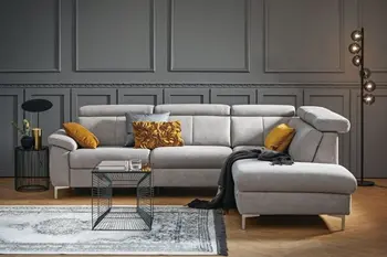 Graues Ecksofa mit klappbaren Kopfstützen und silbernen Füßen in einem Raum mit grauer Stuckwand.