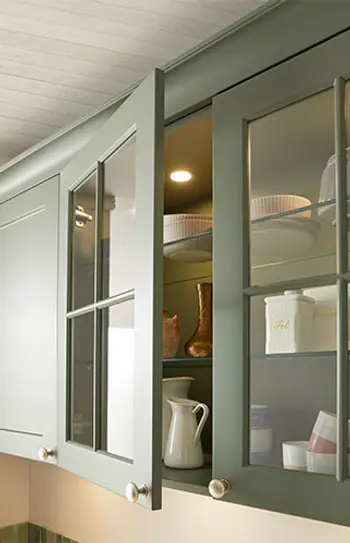 Oberschrank einer grünen Landhausküche.