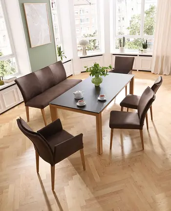 Klassisch eingerichtetes Esszimmer mit Esstisch, braunen Esszimmerstühlen und passender Sitzbank.