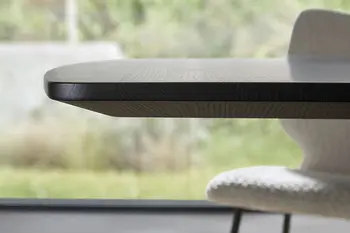 Tischkante eines dunklen Design Esstisches.