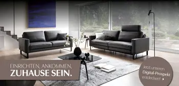 Wohnzimmer mit zwei Sofas; Claim „Zuhause sein“ und Digital-Prospekt-Link.