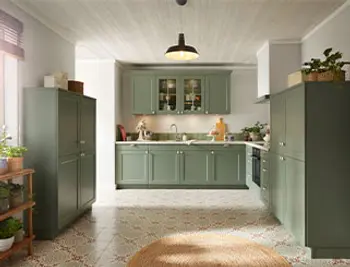 Grüne Landhausküche mit silbernen Griffen und Hochschränken.