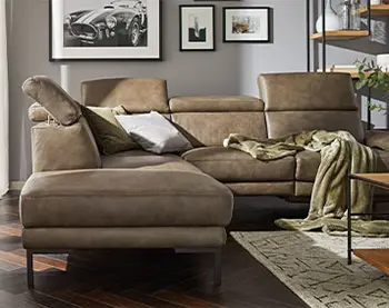 Olivgrünes Ledersofa mit Longchair und hochgeklappten Kopfstützen.