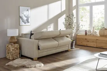 Beiges Schlafsofa, bei dem die Rückenlehnen nach vorne geklappt sind für den Umbau.