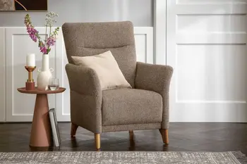 Braun melierter Sessel mit Holzfüßen mit einem beigen Kissen auf der Sitzfläche neben einem roten Beistelltisch mit Blumen und Kerzen.