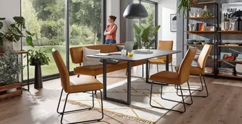 Sitzbank und Stühle mit Lederbezug in camel und schwarzem Gestell in einem hellen Raum um einen schwarzen Esstisch.