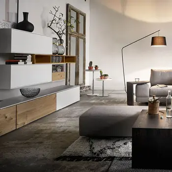 Modernes minimalistisches Wohnzimmer mit großer grauer Eck-Couch, mit vielen Ablagemöglichkeiten in schwarzem Holz. Ein sehr langes Sideboard in Weiß mit Akzenten in Holz und ein Wandregal in der gleichen Optik wie das Sideboard.&nbsp;