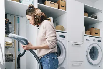 Frau verstaut Staubsauger im Schrank