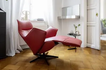 Roter Relaxsessel mit Armlehnen und Lederbezug in Herz-Waage-Position in einem hellen Raum mit Holzboden.