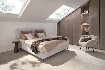 Schlafzimmer in einem modernen Stadthaus mit einem hellgrauen Polsterbett, Beistelltisch und Loungechair. 