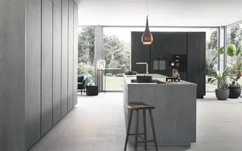 Minimalistische Küche in Betonoptik mit Insel in hellem große Raum.