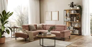 Rosa Ecksofa in einem hellen modernen Wohnzimmer mit einem Couchtisch und Regal im Industrial Look.