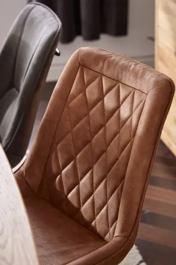 Rückenlehne eines Schalenstuhls für den Esstisch mit Lederbezug in Cognac und einer rautenförmigen Steppung an der Rückenlehne.
