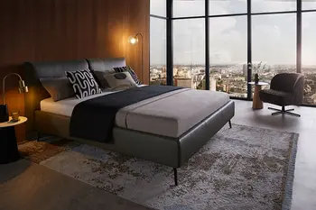 Dunkelgrünes Design Polsterbett neben einem großen Fenster mit Blick auf eine Skyline.