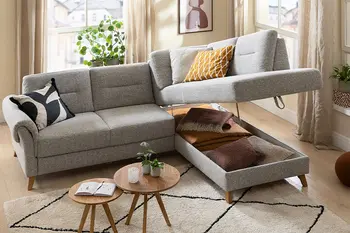 Graues Ecksofa mit integriertem Stauraum unter dem Longchair.