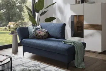 Blaues Sofa, das nur auf der linken Seite eine Armlehen hat und mit zwei Kissen und einer Decke dekoriert ist.