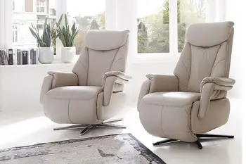 Zwei beige Ledersessel mit Sternfuß und hoher Rückenlehne in einem hellen Raum.