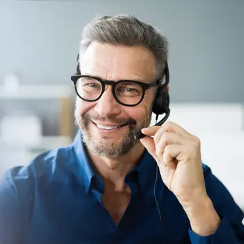Mann rückt mit der Hand das Headsetmikrofon auf seinem Kopf zurecht und lächelt in die Kamera. Recht in Großbuchstaben steht "Kontakt".&nbsp;