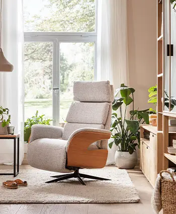 Armlehnstuhl in hellem Stoff mit Holzverkleidung an den Armlehnen.