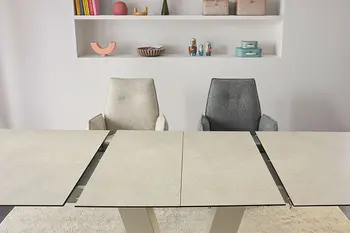 Ausziehbarer Esstisch mit beiger Tischplatte und zwei Armlehnstühlen in grauem und beigem Stoff.