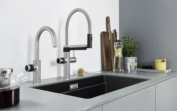 Silberne Filterarmatur mit schwarzem Waschbecken in einer hellen Küche.