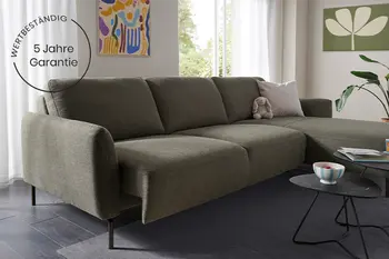 Dunelgrünes Stoffsofa mit Longchair in gemütlichem Wohnzimmre inkl. Garantiehinweis.