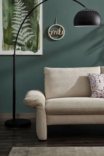 Nach außen geklappte Armlehne eines beigen Sofas.