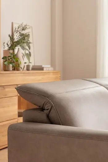 Umgeklappte verstellbare Kopflehne eines grauen Ledersofas.