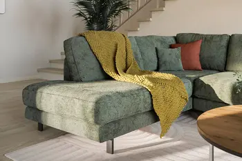 Ein Divan eines grünen Ecksofas für entspanntes Liegen und Füße hochlegen.