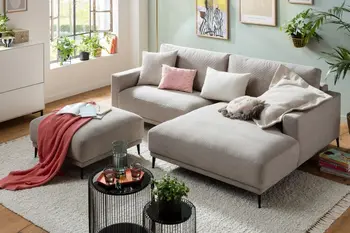 Beiges Ecksofa mit breitem Longchair und schwarzen Füßen.