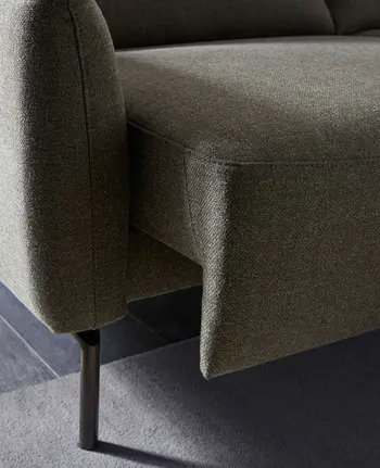 Detailbild von elektrisch ausfahrbarem Sitzvorzug bei grünem Stoffsofa.
