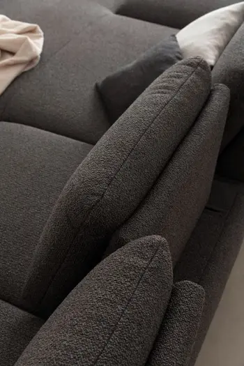 Graues Designersofa, mit nach vorne verstellter Rückenlehne.