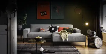 Graues Stoffsofa mit schwarzen Couchtisch in dunklem, gemütlichen Wohnzimmer.