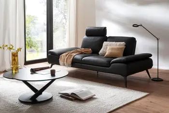 Schwarzes Leder 3-Sitzer Sofa mit einer aufgeklappten Kopfstütze in einem hellen Raum.
