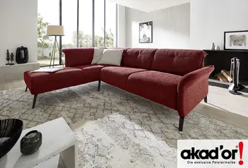 Rote Eckcouch der Marke akador in einem modern eingerichteten Wohnzimmer mit großen Fensterfronten, Teppich und minimalistischer Dekoration.