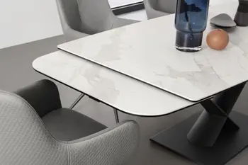 Moderner weißer Esstisch mit einer Keramiktischplatte im Marmor Look, bei dem die Verlängerungsplatte fast vollständig ausgezogen wurde.
