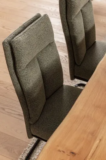 Zwei grüne Freischwinger an einem Esstisch.