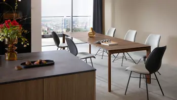 Großer Massivholz Esstisch um den mehrere Design Schalenstühle stehen.